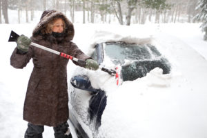 woman shoveling snow off of her car