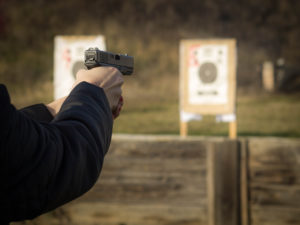 Gun in girl's hands on shooting range