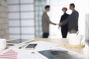 close-up of business items with people meeting in background