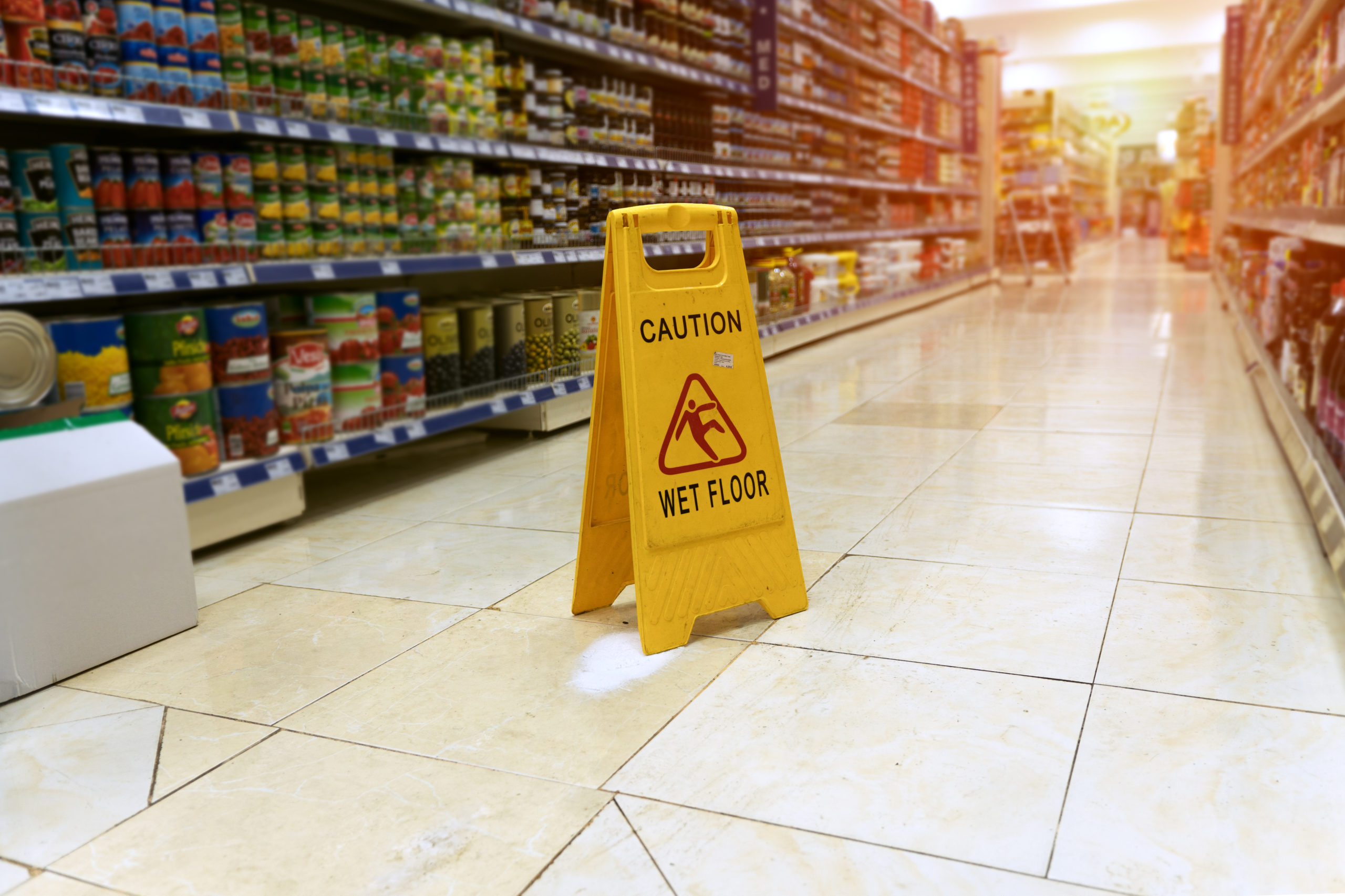 slip and fall sign in the middle of grocer isle