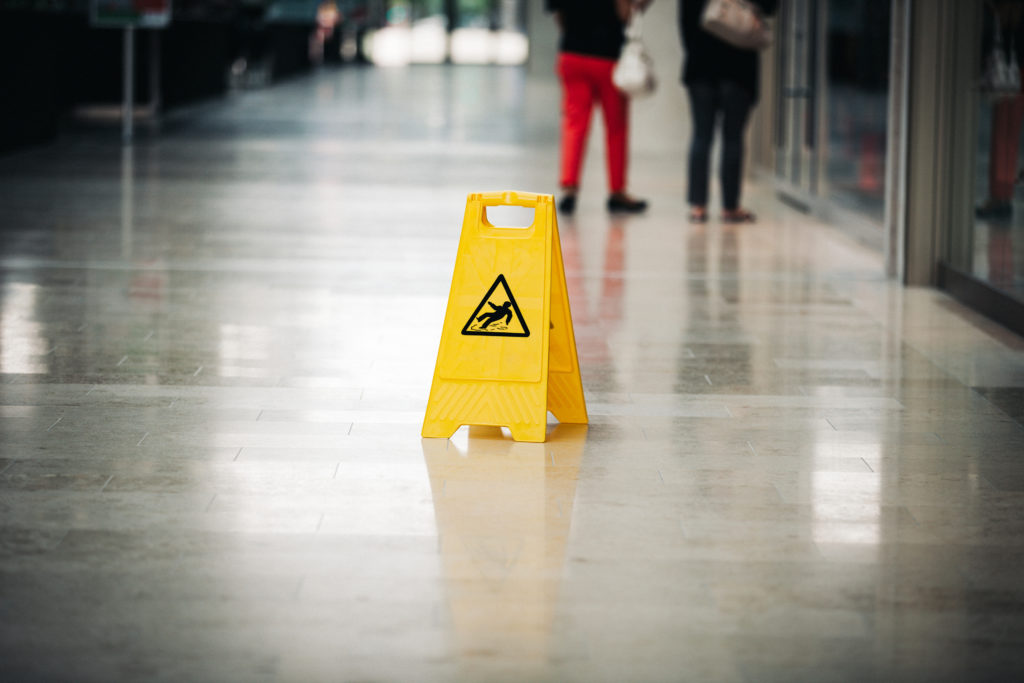 two people walk by a slip and fall sign
