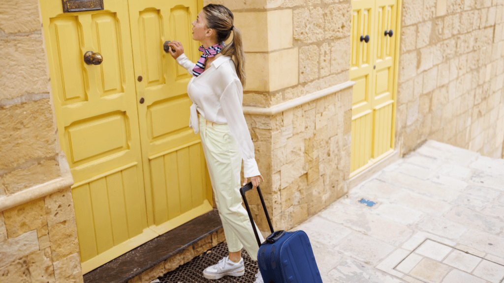 Woman carrying a suitcase entering an Airbnb property