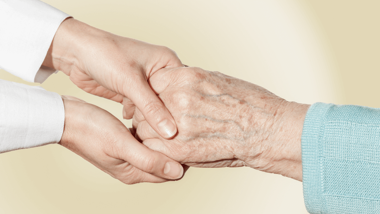 A caregiver holding an elderly person's hand
