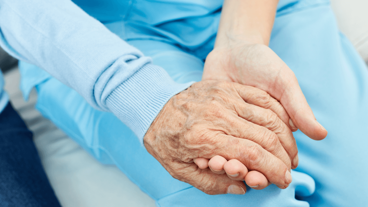 A caregiver holding an elder's hand