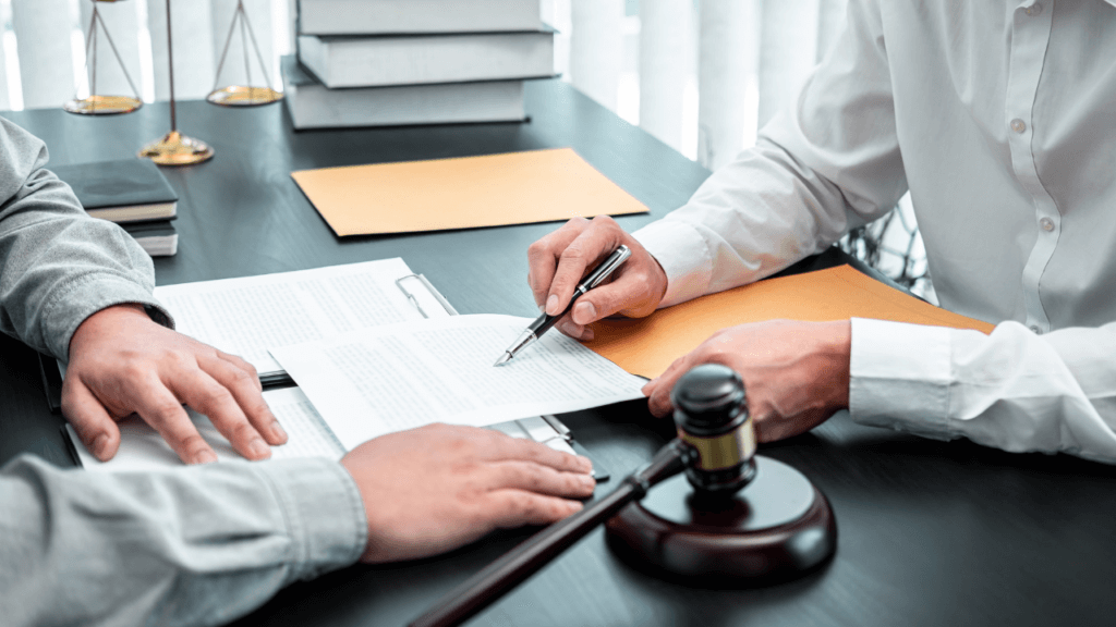 A person signing documents with his lawyer.