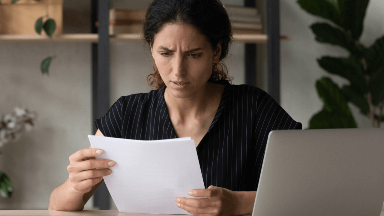 A woman reading documents with a distressed look.