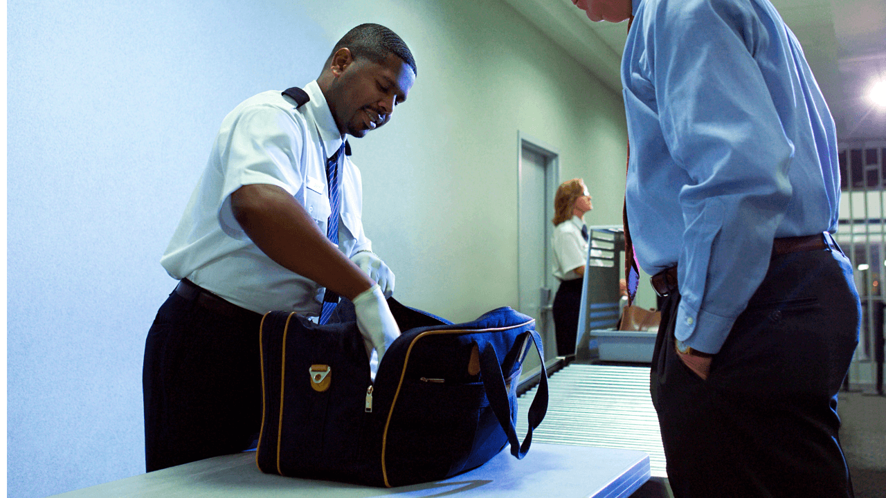 An airport security personnel inspecting a passenger's luggage.