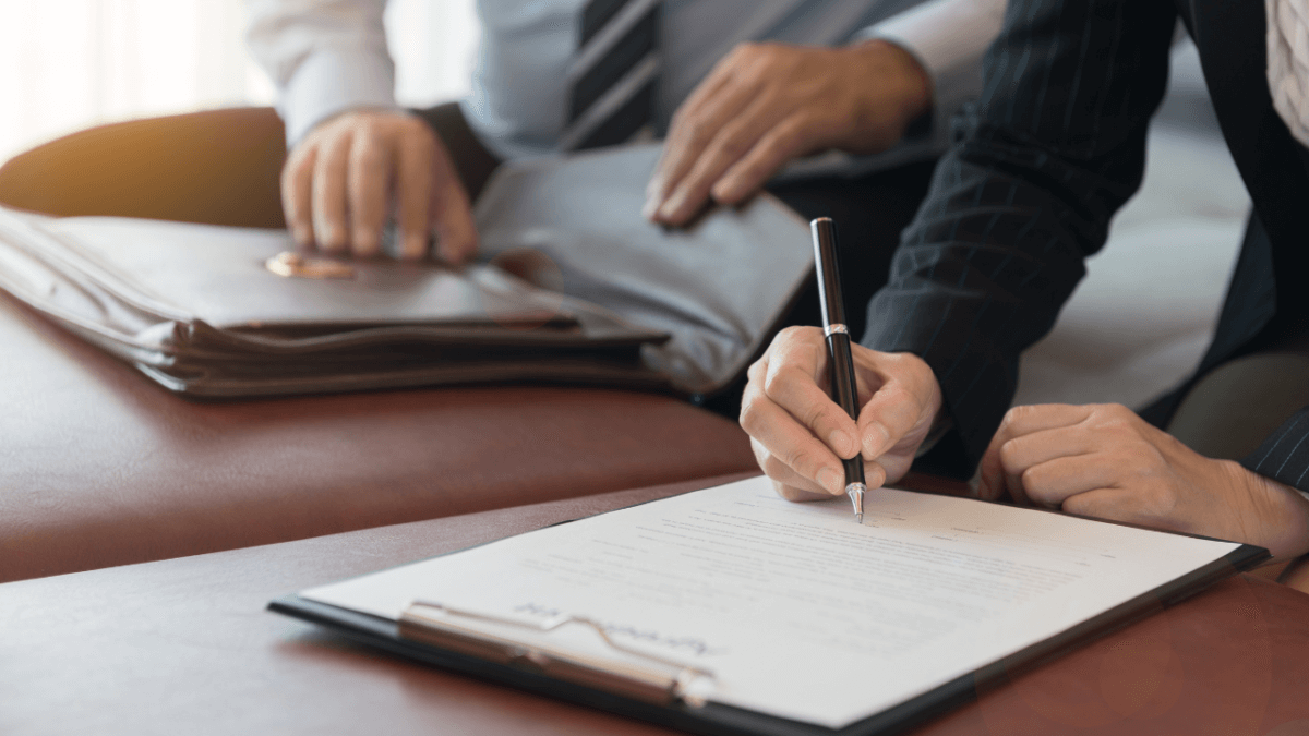 Person signing legal documents during a probate consultation, with another individual reviewing materials, emphasizing the importance of final accounting and distribution in estate management.