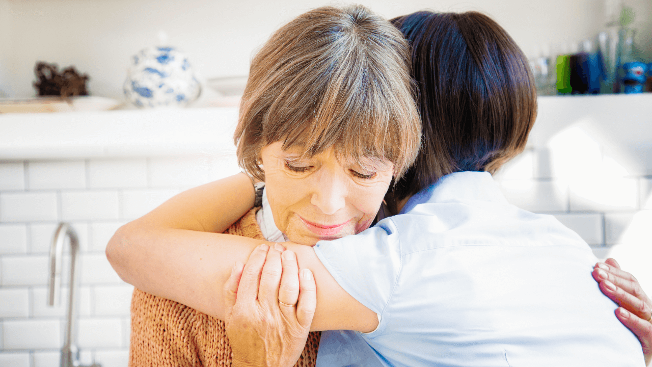 An elderly woman hugging a younger woman.