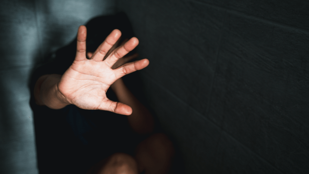 A photo of a woman holding out her hand to defend herself.