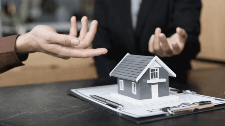 A photo of a model house and two people pointing to it.